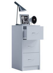 Heller, moderner Nachttisch/Kommode mit drei Schubladen und Chromgriffen, eine Schublade leicht geöffnet; darauf schwarze Tischlampe, Bilderrahmen und runder Wecker, freigestellt auf weißem Hintergrund, Perspektive: frontale leicht seitliche Ansicht von l