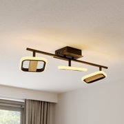 Moderne LED-Deckenleuchte in Schwarz mit drei Lichtmodulen und Holzdetails, warmweiß leuchtend, aus Untersicht/Deckenperspektive im Wohnraum fotografiert