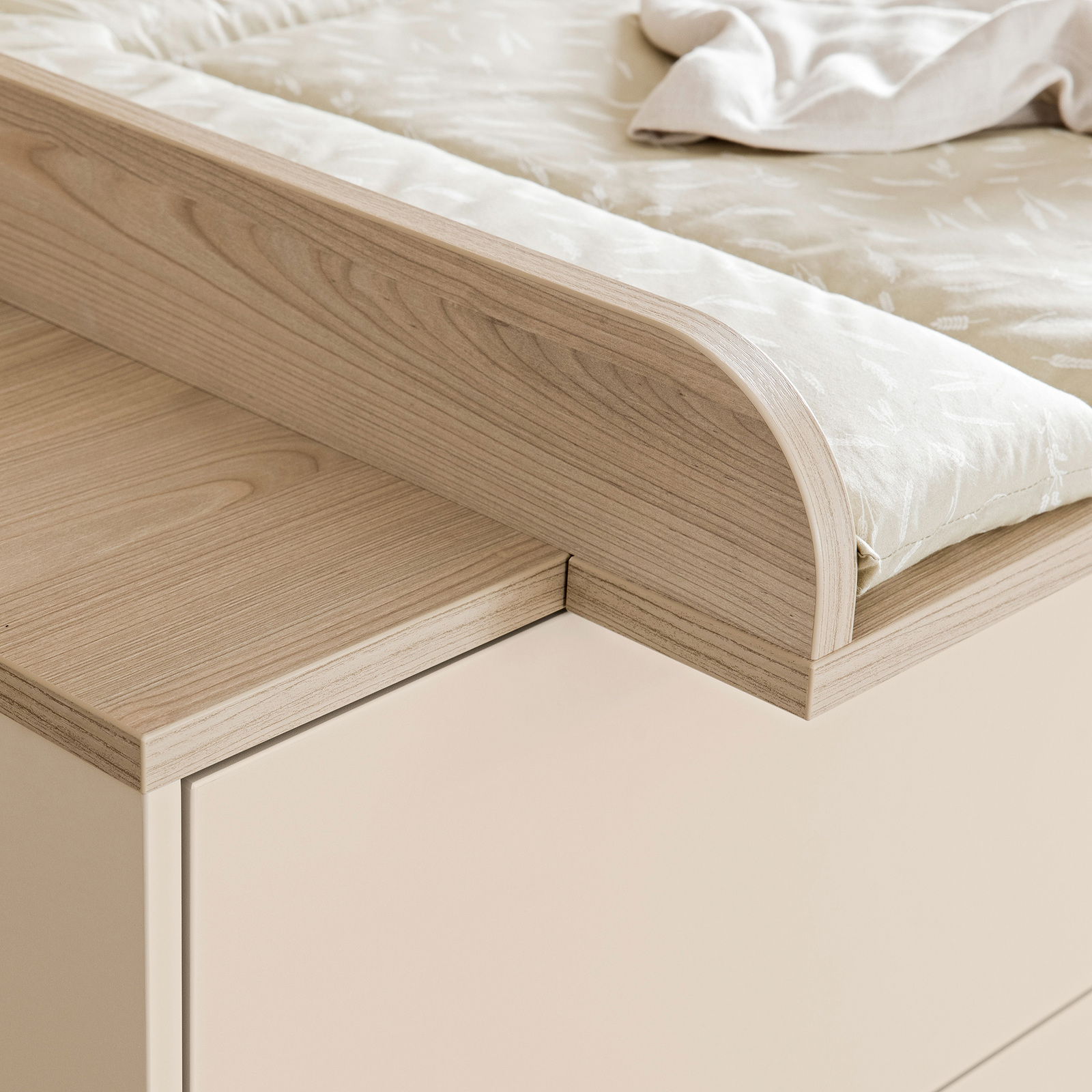 Nahaufnahme eines Wickelaufsatzes aus hellem Holz mit abgerundeten Kanten, von der Seite betrachtet.