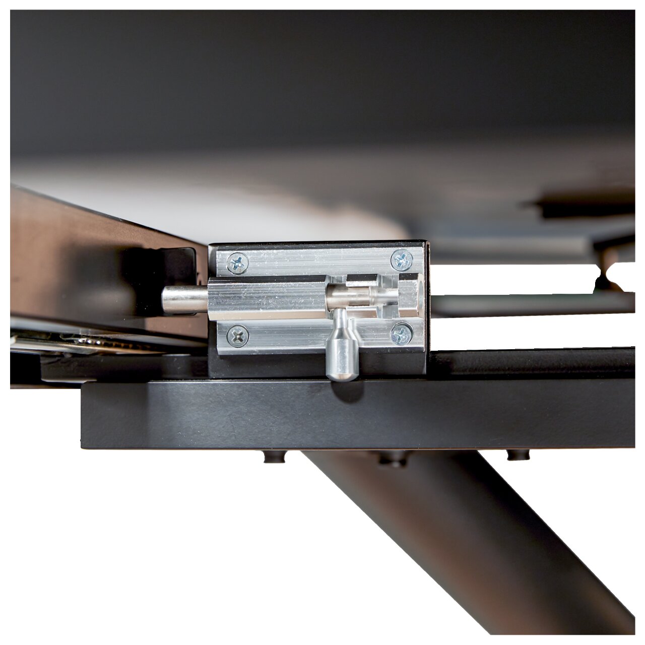 Close-up van een metalen mechanisme onder een tafel, zijaanzicht