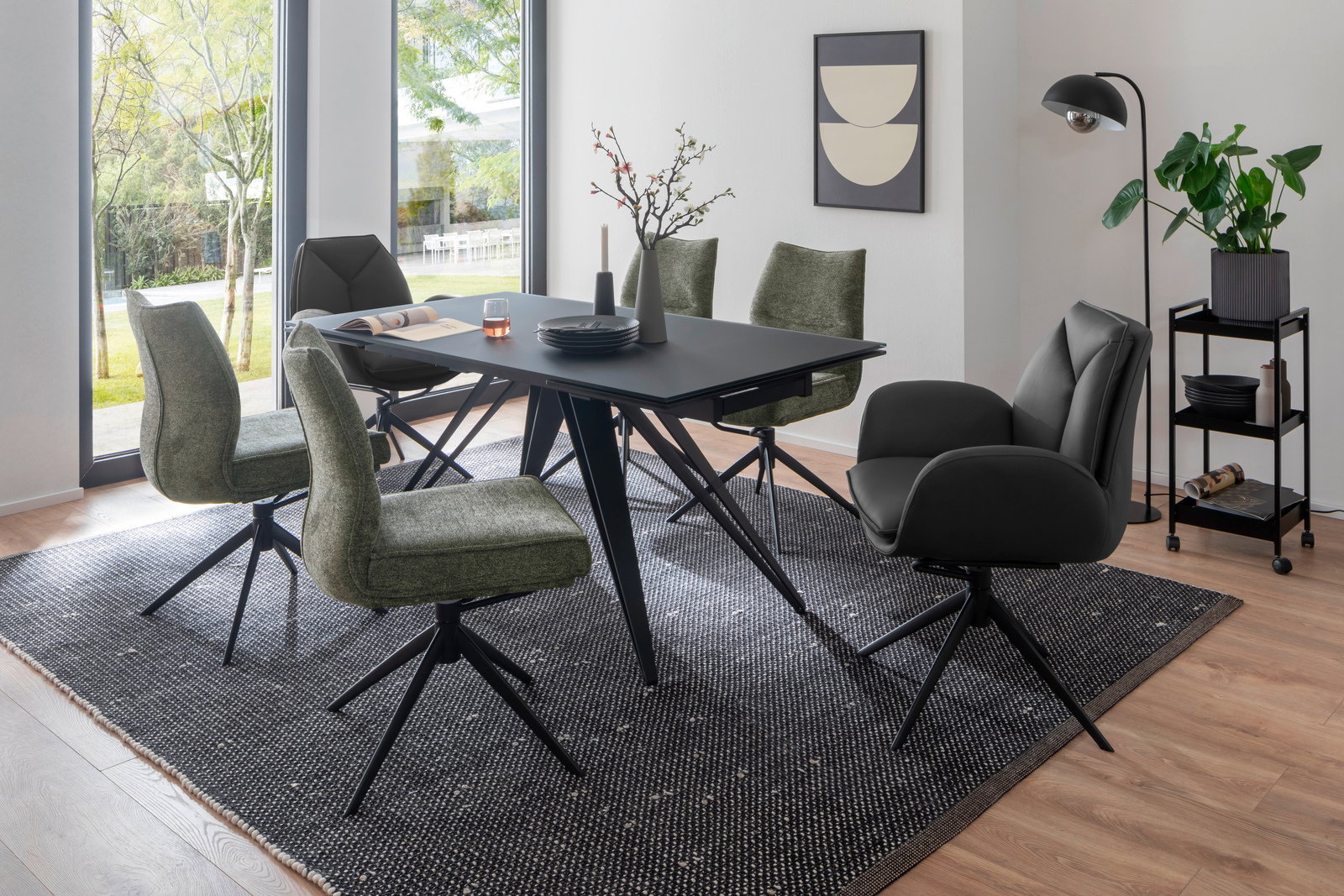 Esszimmer mit modernem Tisch und Stühlen in einem hellen Raum mit großen Fenstern, seitliche Perspektive.