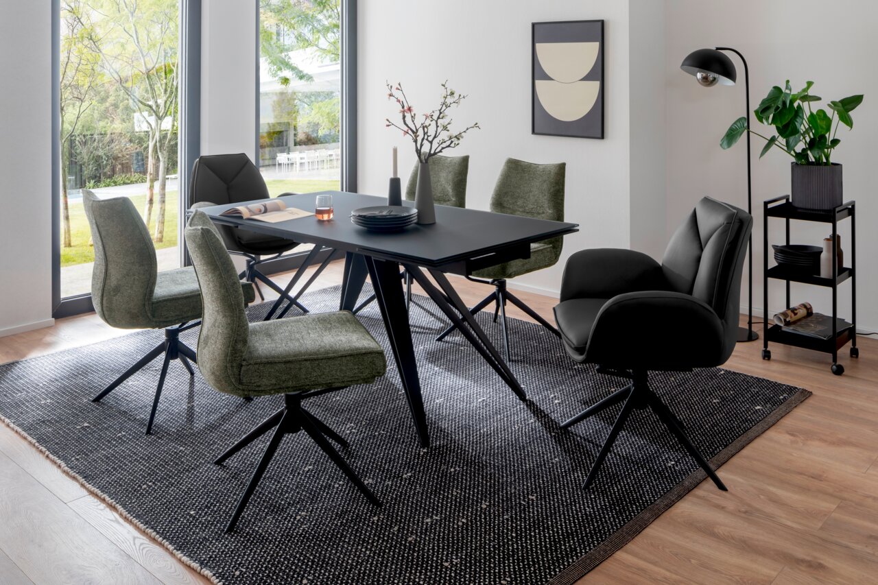 Esszimmer mit modernem Tisch und Stühlen in einem hellen Raum mit großen Fenstern, seitliche Perspektive.