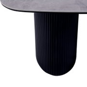 Close-up van een salontafel met een ronde, geribbelde poot en een glad blad.