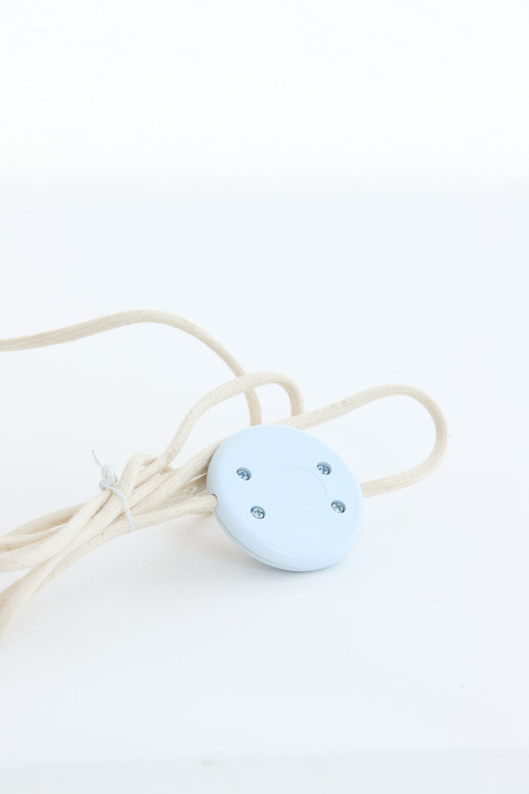 Nahaufnahme eines weißen Kabels mit einem runden, blauen Schalter, Teil einer Stehleuchte.