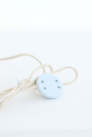 Nahaufnahme eines weißen Kabels mit einem runden, blauen Schalter, Teil einer Stehleuchte.