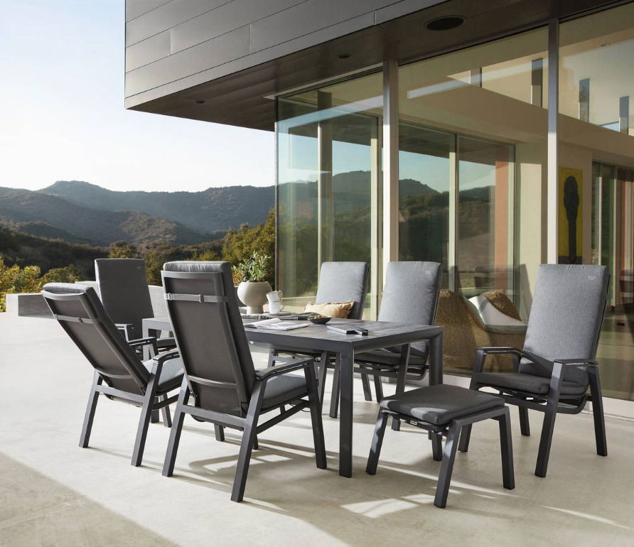 Moderne Gartenmöbel-Sitzgruppe mit Hochlehner-Stühlen und Tisch auf einer Terrasse mit Bergblick, seitliche Perspektive