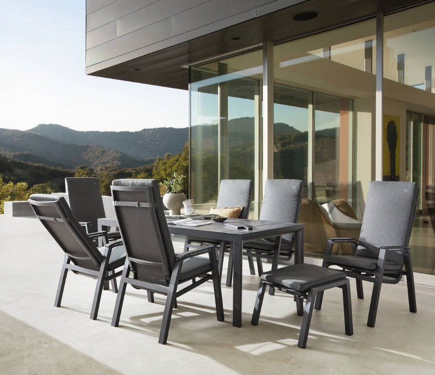 Moderne Gartenmöbel-Sitzgruppe mit Hochlehner-Stühlen und Tisch auf einer Terrasse mit Bergblick, seitliche Perspektive