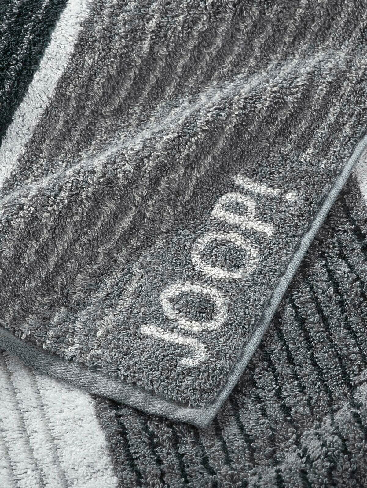 Graues Handtuch mit eingewebtem Schriftzug 'JOOP!' in Nahaufnahme, zeigt die weiche Textur und das Streifenmuster.