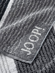 Graues Handtuch mit eingewebtem Schriftzug 'JOOP!' in Nahaufnahme, zeigt die weiche Textur und das Streifenmuster.