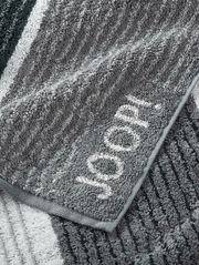 Graues Handtuch mit eingewebtem Schriftzug 'JOOP!' in Nahaufnahme, zeigt die weiche Textur und das Streifenmuster.