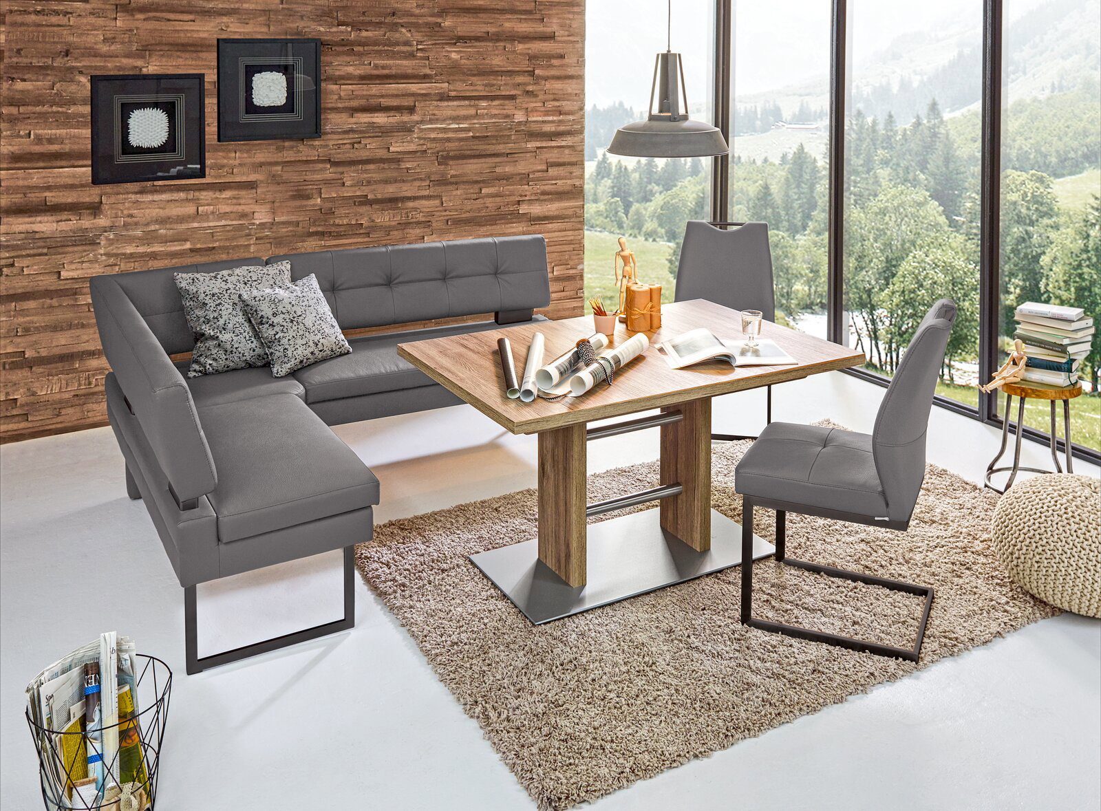 Moderne Eckbank in grauem Leder mit passendem Esstisch und Stühlen, in einem hellen Raum mit großen Fenstern und Holzwand, aus der Vogelperspektive.
