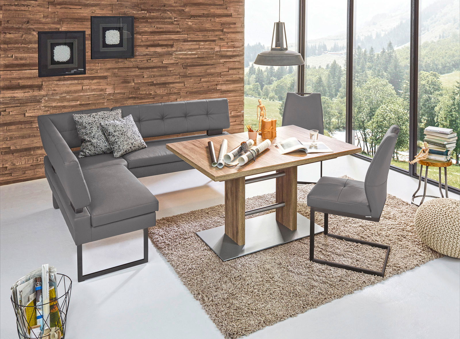 Moderne Eckbank in grauem Leder mit passendem Esstisch und Stühlen, in einem hellen Raum mit großen Fenstern und Holzwand, aus der Vogelperspektive.