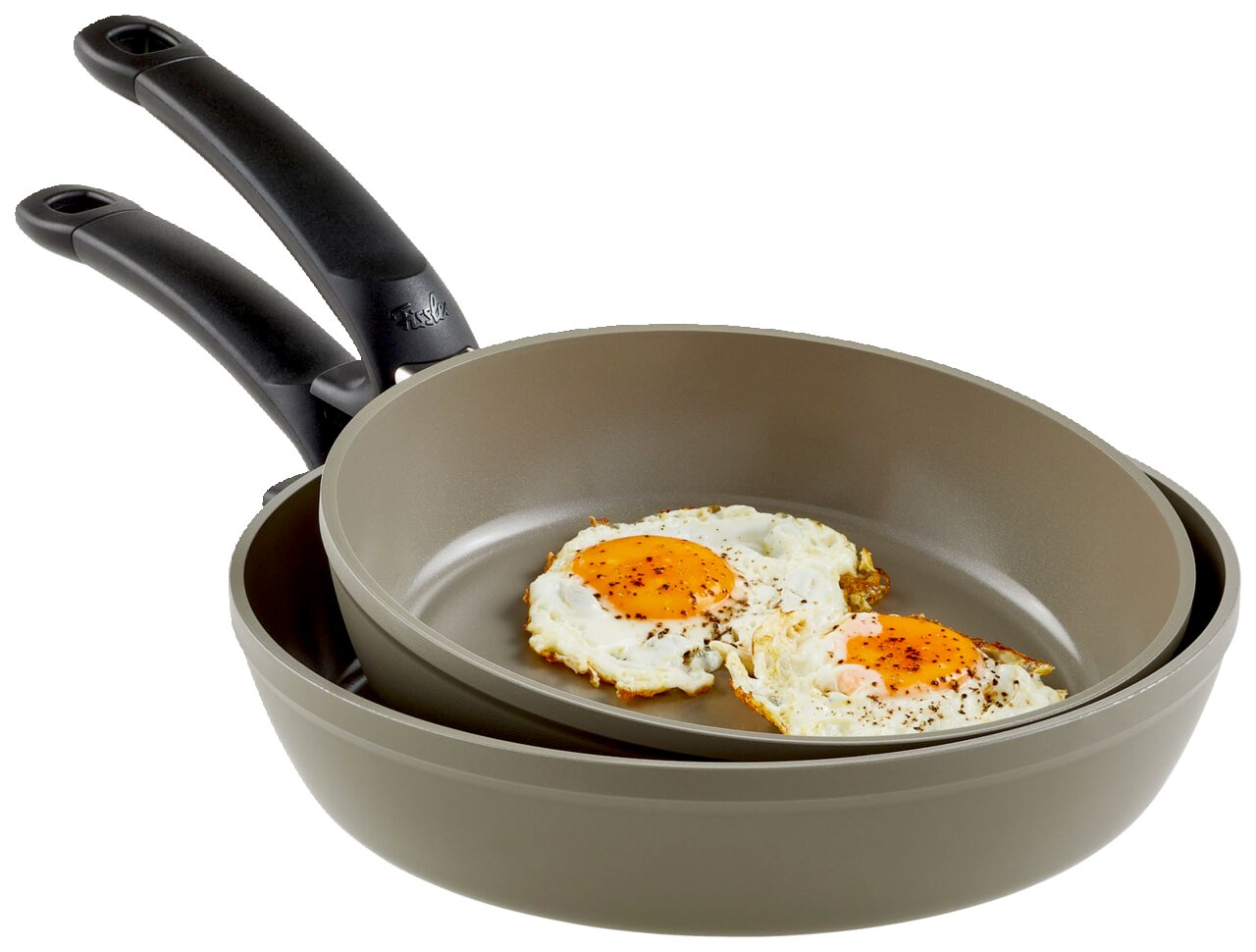 Fissler Pfannenset 2-tlg.Ceratal Comfort Zwei Pfannen des Pfannensets Ceratal Comfort, übereinander gestapelt, mit Spiegeleiern in der oberen Pfanne, seitliche Perspektive.