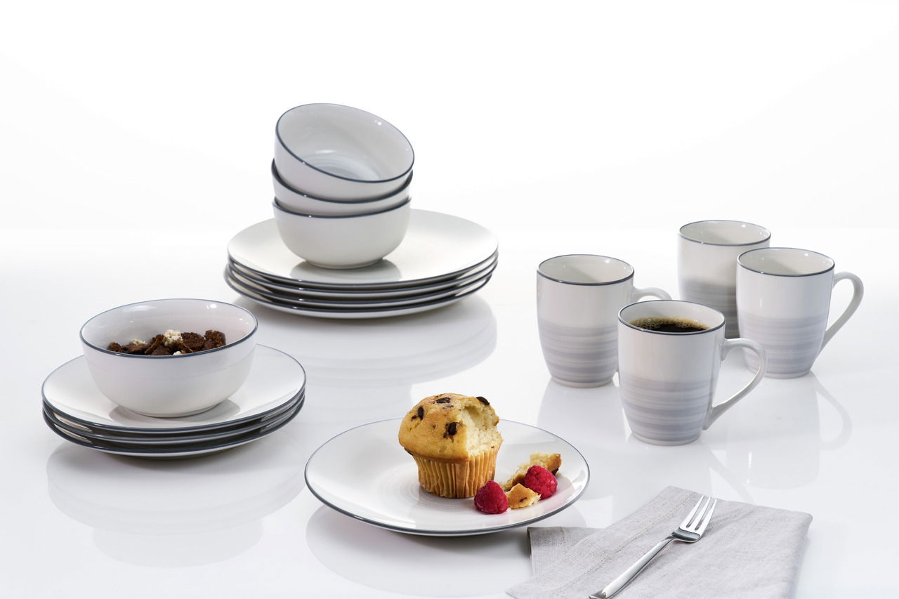 Kombiservice 16-tlg. in moderner Perspektive, bestehend aus Tellern, Schalen und Tassen, präsentiert auf einem weißen Hintergrund mit einem Muffin und Himbeeren.