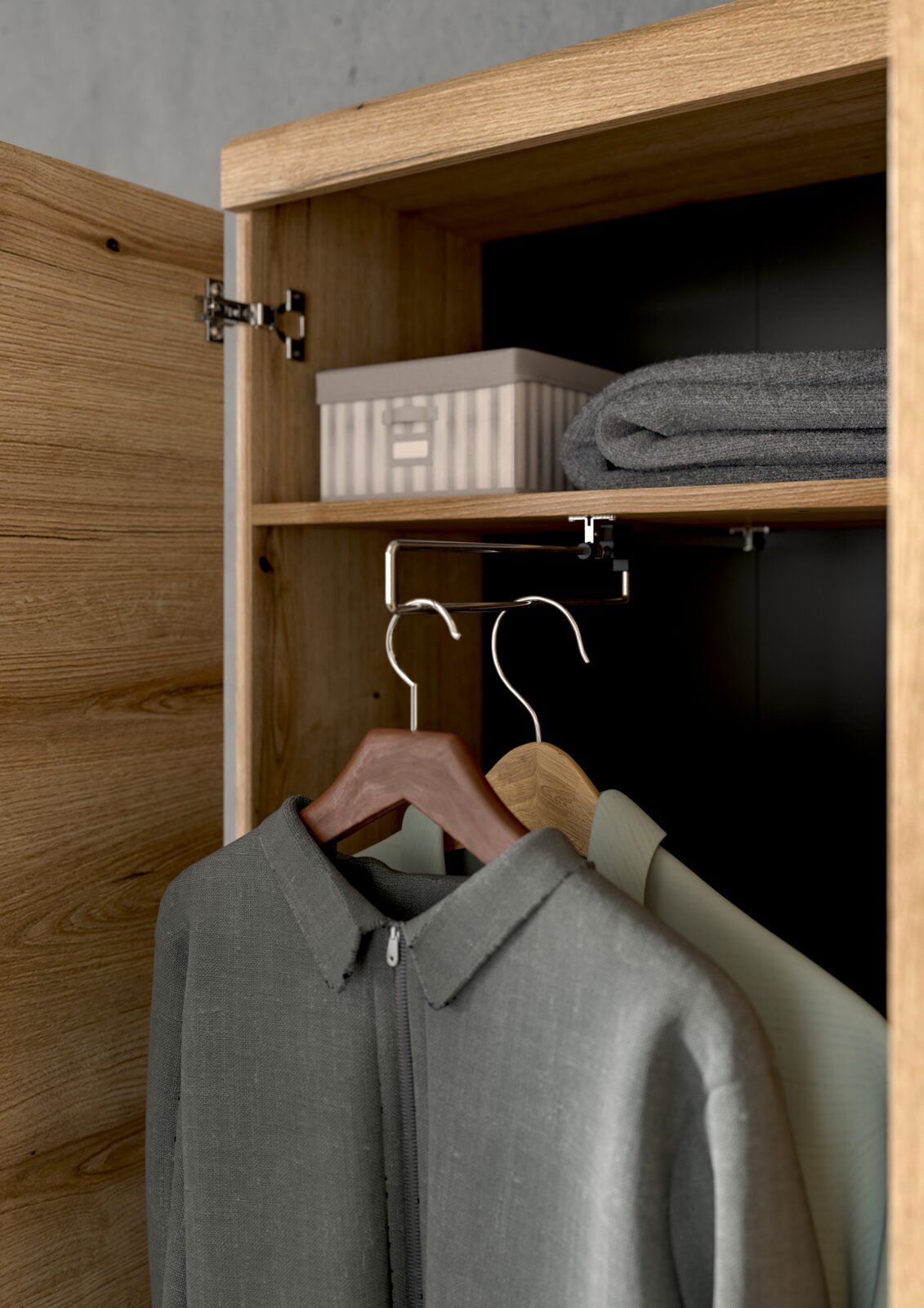 Innenansicht eines Holzschranks mit geöffneter Tür, zeigt Kleiderbügel mit Kleidung, ein Regal mit einer Box und einem gefalteten Handtuch.