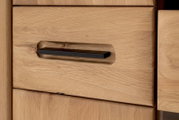 Nahaufnahme einer Holzschublade mit einem schwarzen, modernen Griff, perspektivisch von vorne aufgenommen.