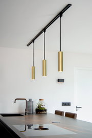 Moderne Pendelleuchte FLORIS in mattgold, dreifach von der Decke hängend über einer Kücheninsel, seitliche Perspektive.