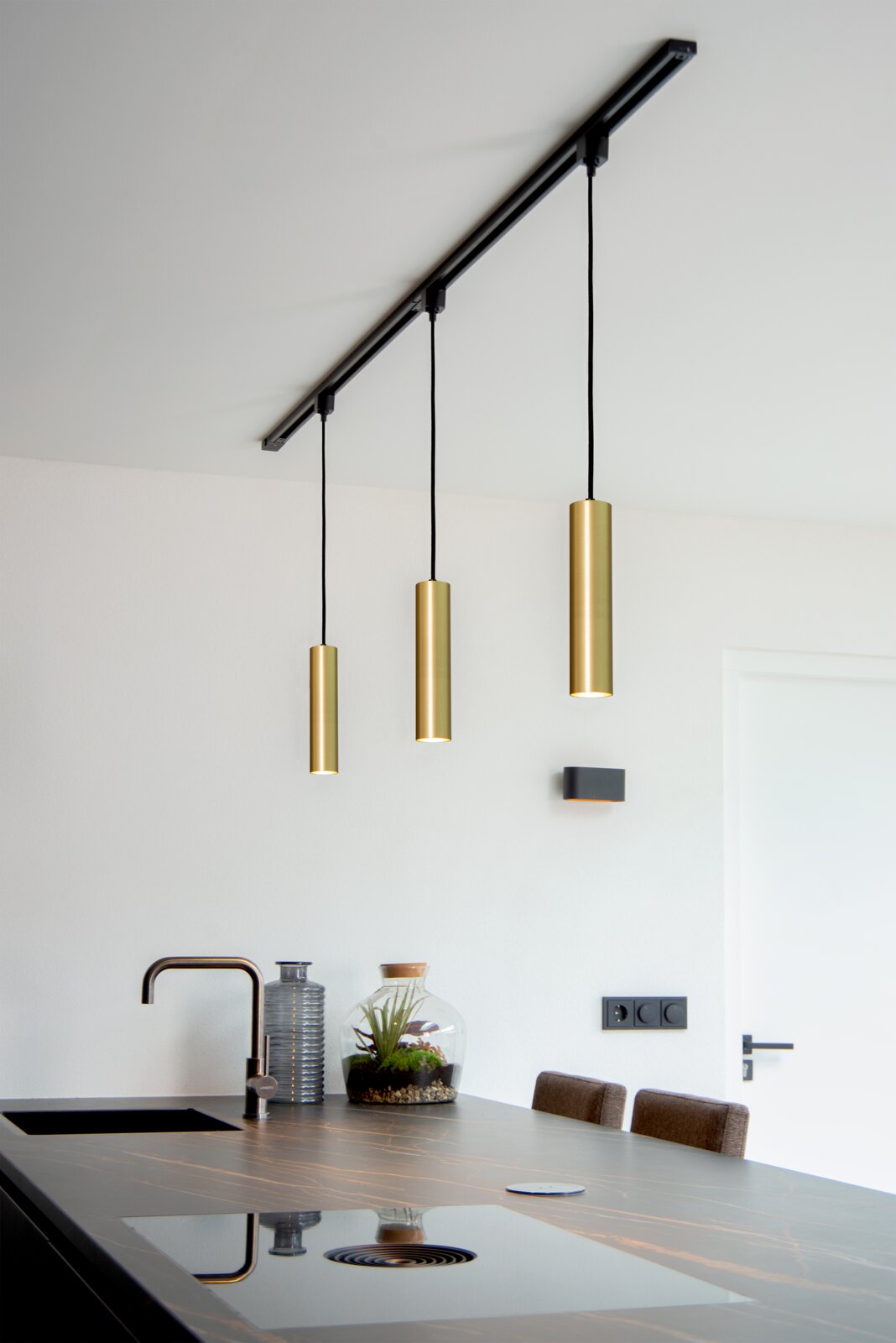 Moderne Pendelleuchte FLORIS in mattgold, dreifach von der Decke hängend über einer Kücheninsel, seitliche Perspektive.