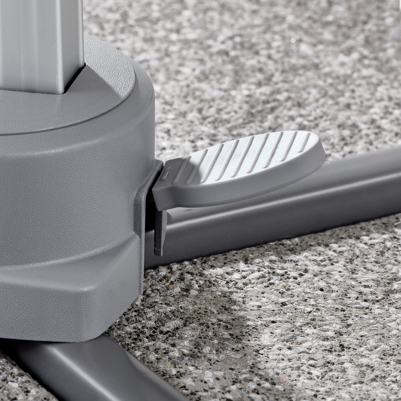Nahaufnahme eines grauen Fußpedals an der Basis eines Ampelschirms auf einer Steinoberfläche.