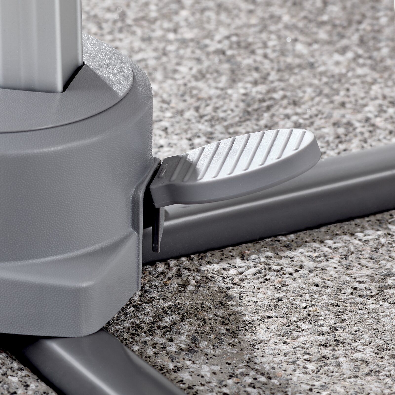 Nahaufnahme eines grauen Fußpedals an der Basis eines Ampelschirms auf einer Steinoberfläche.