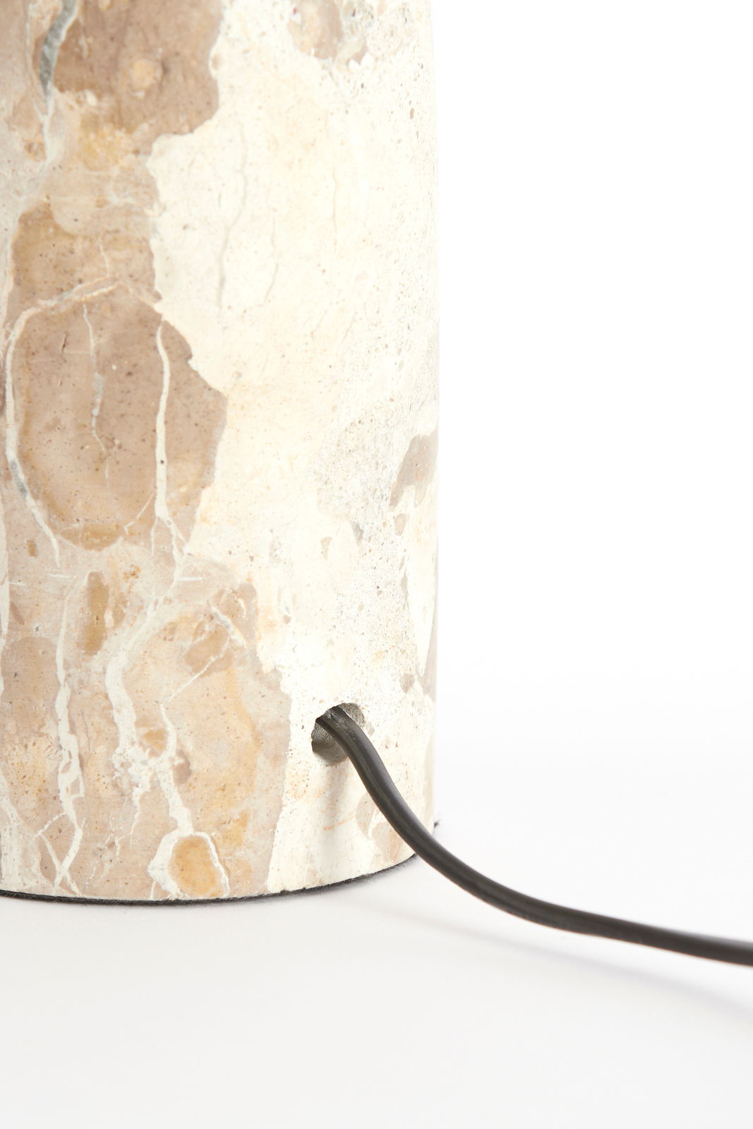 Nahaufnahme eines Lampenfußes aus Marmor mit sichtbarem Stromkabel, seitliche Perspektive.