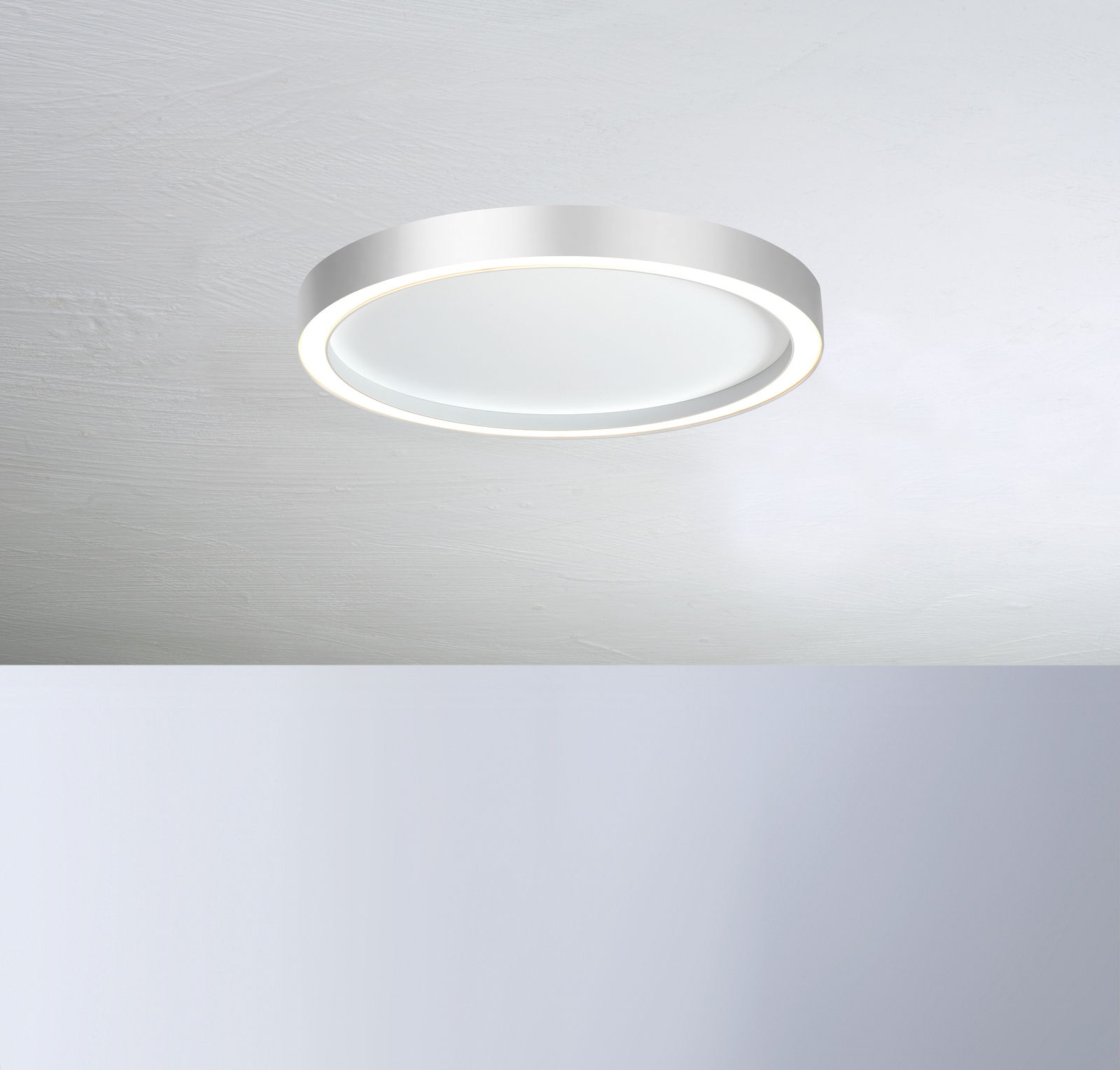 Moderne runde Deckenleuchte AURA in Weiß, von unten betrachtet, mit sanftem Lichtschein.