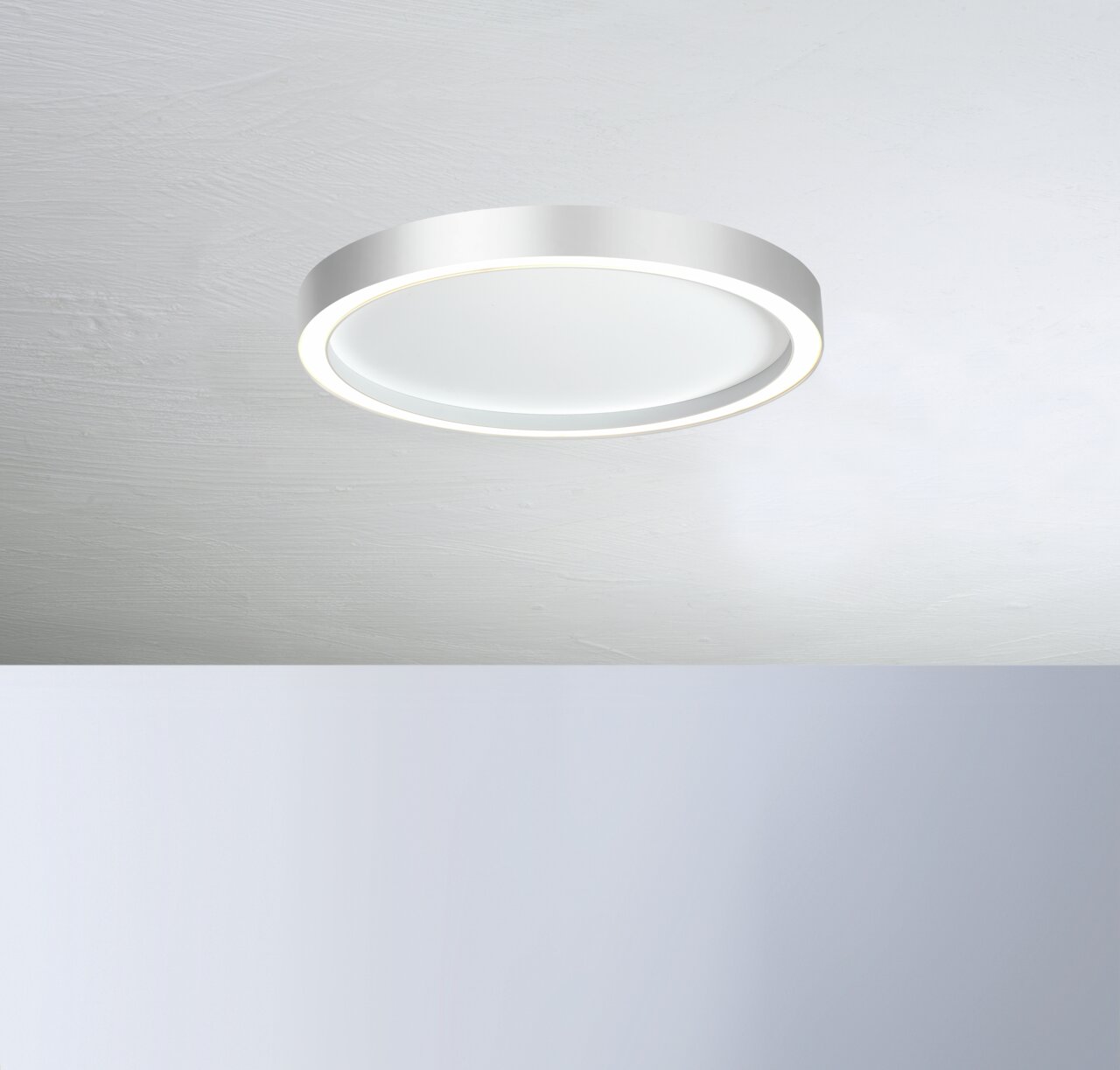 Moderne runde Deckenleuchte AURA in Weiß, von unten betrachtet, mit sanftem Lichtschein.