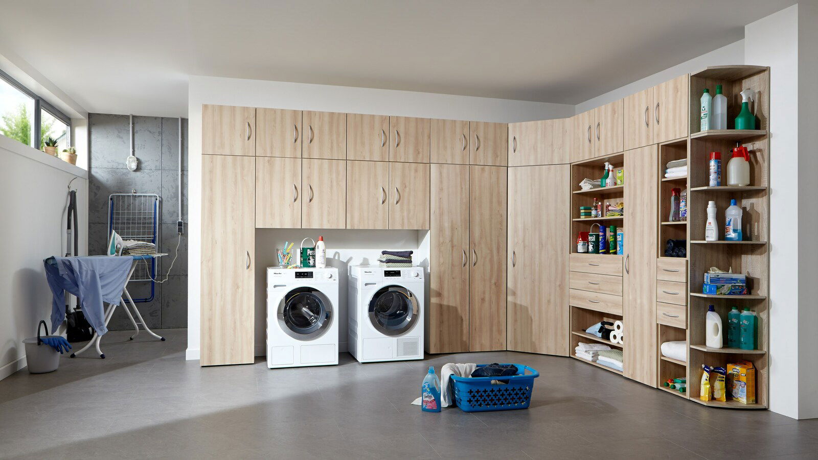 Eckschrank-Aufsatz in einer Waschküche mit Holzoptik, umgeben von Waschmaschinen und Regalen, perspektivisch von vorne rechts.