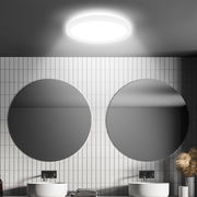 Moderne LED-Deckenleuchte mit Bewegungssensor, von unten betrachtet, in einem stilvollen Badezimmer mit zwei runden Spiegeln und weißen Fliesen.