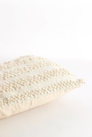 Nahaufnahme eines strukturierten, cremefarbenen Kissens mit dekorativem Muster, seitliche Perspektive