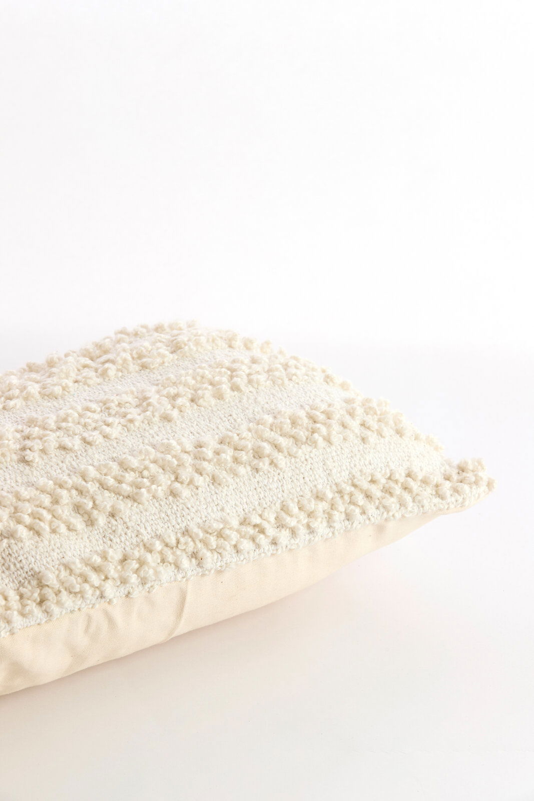 Nahaufnahme eines strukturierten, cremefarbenen Kissens mit dekorativem Muster, seitliche Perspektive