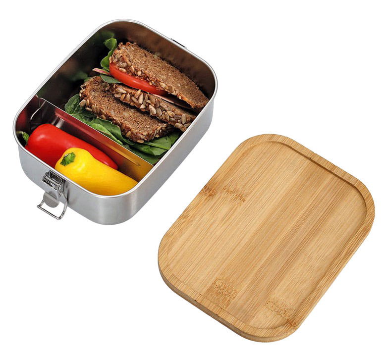 Lunchbox aus Edelstahl mit Clipverschluss, gefüllt mit einem belegten Vollkornbrot, Paprika und Salat. Der Deckel aus Holz liegt daneben. Perspektive von oben.