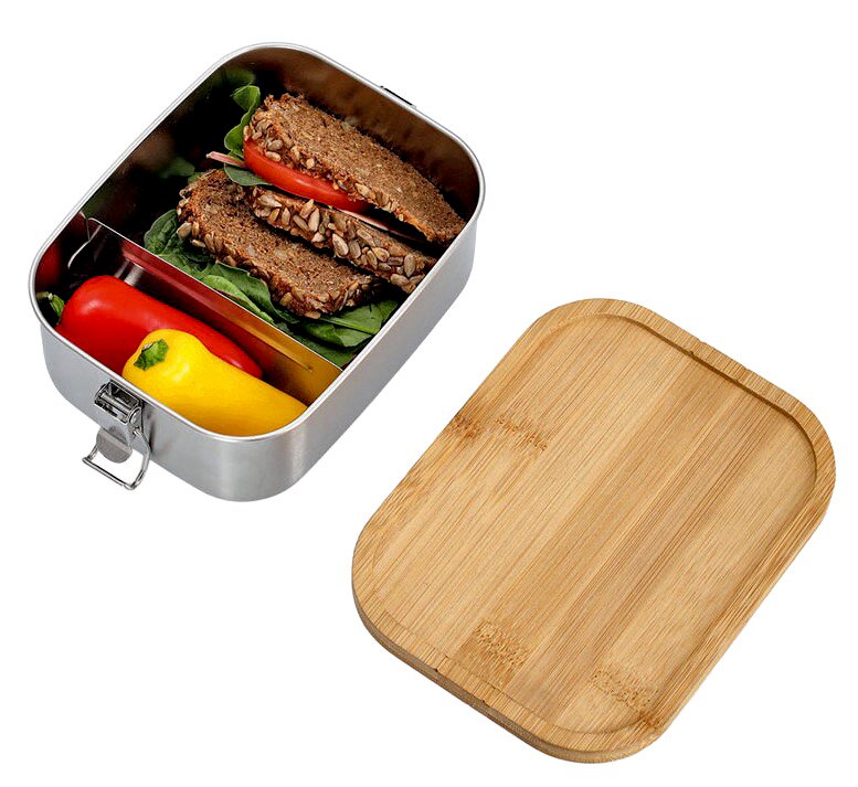 Lunchbox aus Edelstahl mit Clipverschluss, gefüllt mit einem belegten Vollkornbrot, Paprika und Salat. Der Deckel aus Holz liegt daneben. Perspektive von oben.