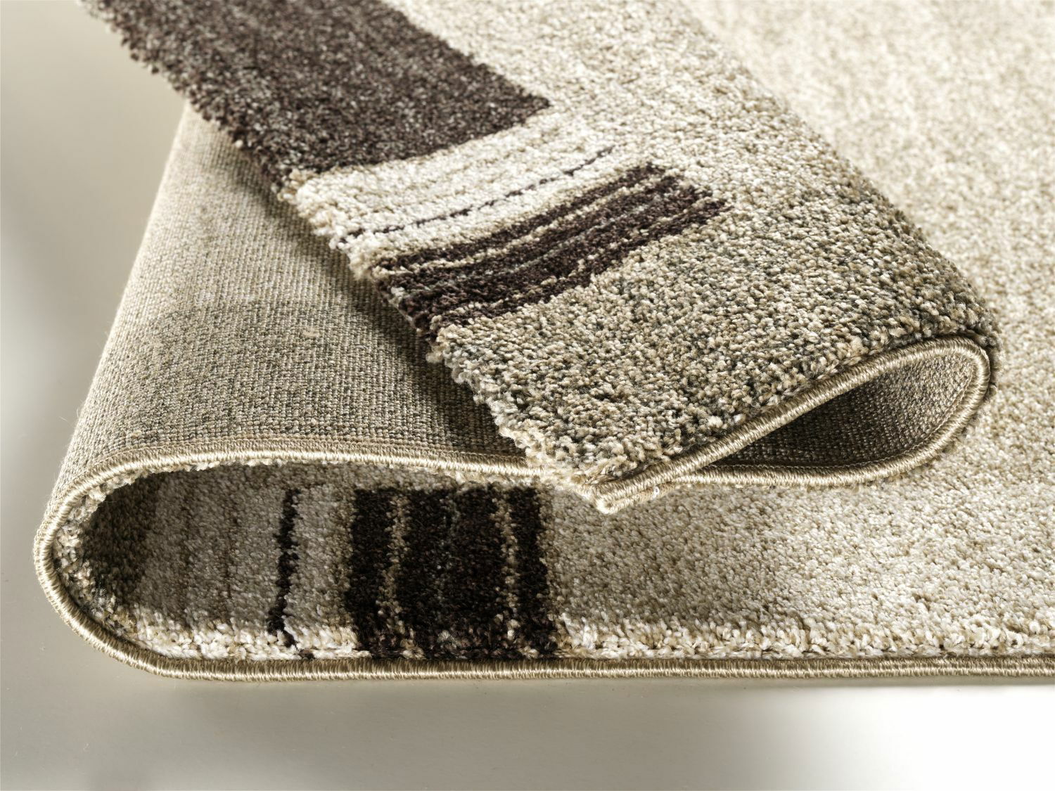 Nahaufnahme eines beigen Teppichs mit braunen Streifen, der an einer Ecke umgeschlagen ist.