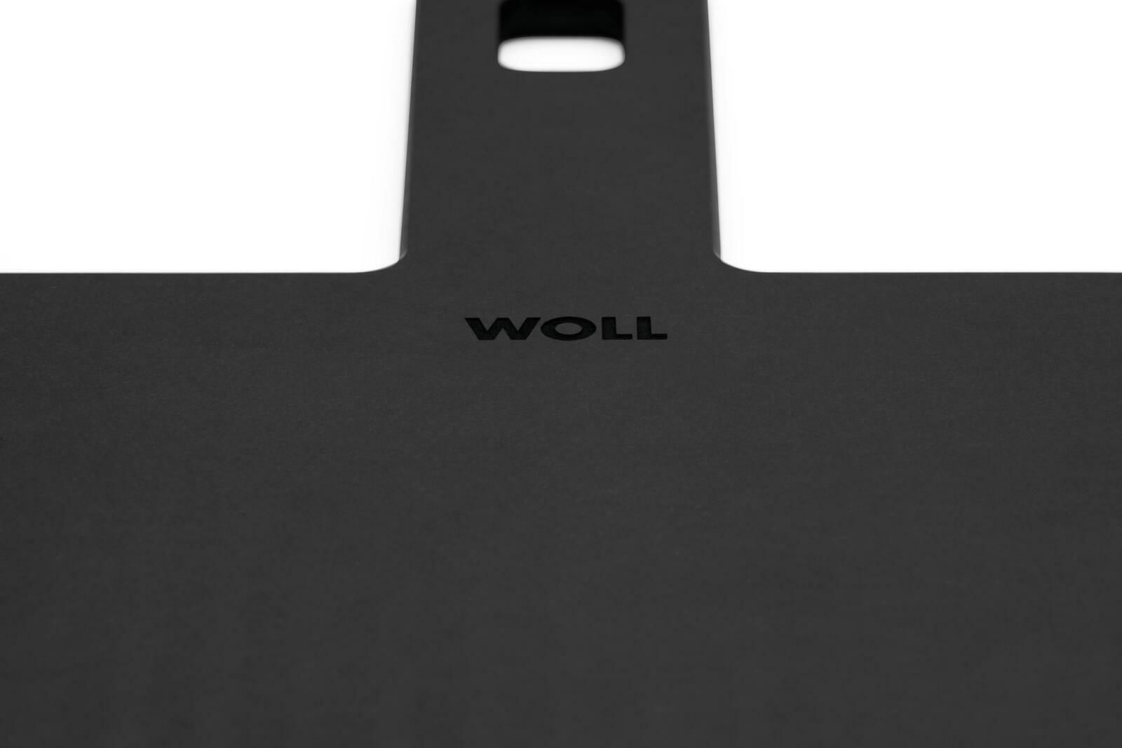 Nahaufnahme eines schwarzen Schneidebretts mit dem Logo 'WOLL' in der Mitte, perspektivisch von oben fotografiert.