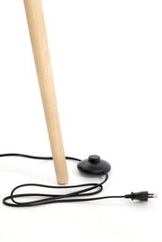 Nahaufnahme eines Holzbeins einer Stehleuchte mit schwarzem Fußschalter und Stromkabel auf weißem Hintergrund.