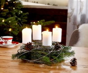 Silberner Dekokranz für 4 Kerzen mit Tannenzweigen und Zapfen, auf einem Tisch in weihnachtlicher Umgebung, seitliche Perspektive