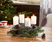 Silberner Dekokranz für 4 Kerzen mit Tannenzweigen und Zapfen, auf einem Tisch in weihnachtlicher Umgebung, seitliche Perspektive