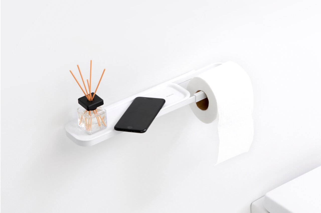 Moderner Toilettenpapierhalter mit Ablage, seitliche Perspektive, mit Duftstäbchen und Smartphone auf der Ablage.
