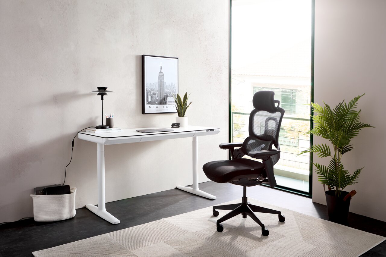 Moderner weißer E-Schreibtisch in einem hellen Raum, seitliche Perspektive, mit einem ergonomischen schwarzen Bürostuhl und einer Pflanze im Hintergrund.