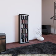 Schmales schwarzes CD-/DVD-Regal mit mehreren Fächern, gefüllt mit Medienhüllen, im Wohnzimmer an einer weißen Wand; Perspektive: leicht schräg von vorn aus Augenhöhe.