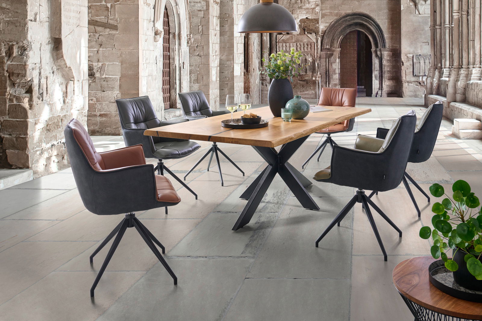 Linea Natura Esstisch 240x100 HERO Moderner Esstisch mit Holzplatte und Metallgestell, umgeben von stilvollen Drehstühlen in einem historischen Raum, seitliche Perspektive.