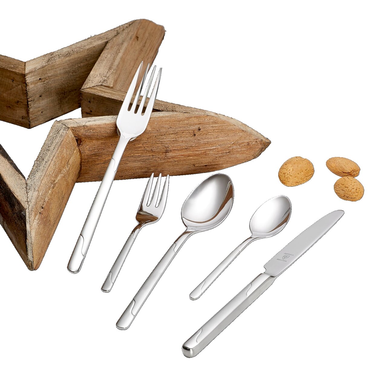 Elegantes Besteckset Viva 60-tlg. aus Edelstahl, bestehend aus Messer, Gabel, Löffel und Teelöffel, auf schwarzem Hintergrund mit Holzstern und Mandeln, aus der Vogelperspektive.