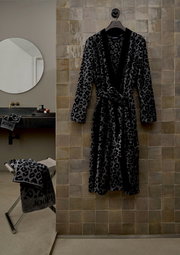 Leopardenmuster Bademantel in einer modernen Badezimmerumgebung, frontal an einer Wand hängend.