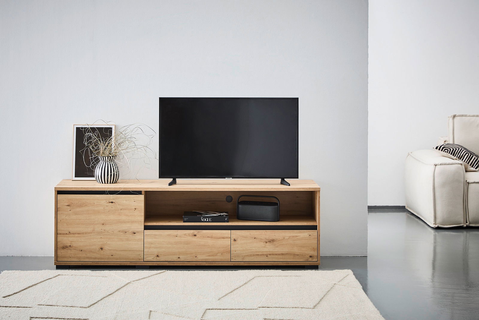 Carryhome TV-Lowboard LINE TV-Lowboard aus Holz mit modernem Design, frontal fotografiert. Auf dem Lowboard steht ein Fernseher, daneben eine Vase mit Pflanzen und ein gerahmtes Bild.
