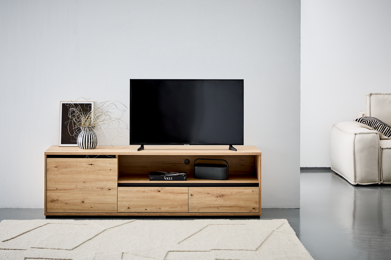 Carryhome TV-Lowboard LINE TV-Lowboard aus Holz mit modernem Design, frontal fotografiert. Auf dem Lowboard steht ein Fernseher, daneben eine Vase mit Pflanzen und ein gerahmtes Bild.