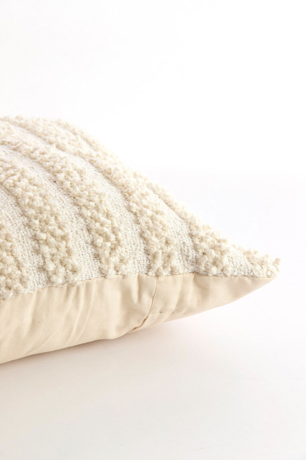 Nahaufnahme eines cremefarbenen Kissens mit strukturierter Oberfläche, seitliche Perspektive