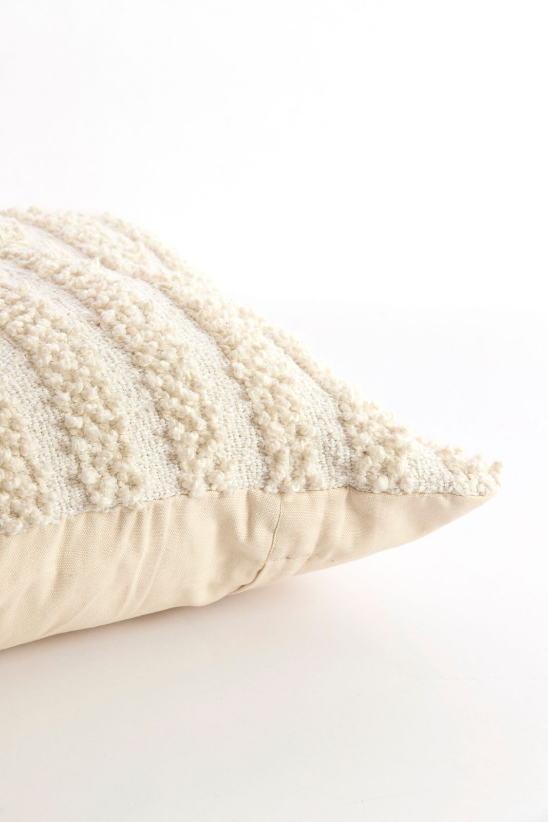 Nahaufnahme eines cremefarbenen Kissens mit strukturierter Oberfläche, seitliche Perspektive