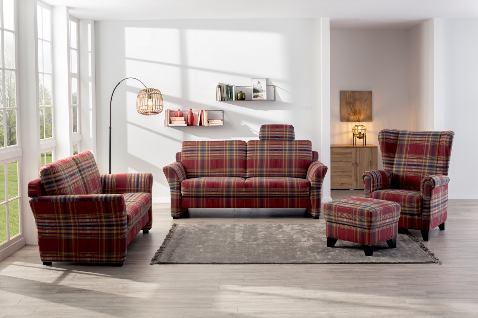 Wohnzimmer mit einem 3er-Sofa, Sessel und Hocker in rot-kariertem Stoff, von vorne betrachtet.