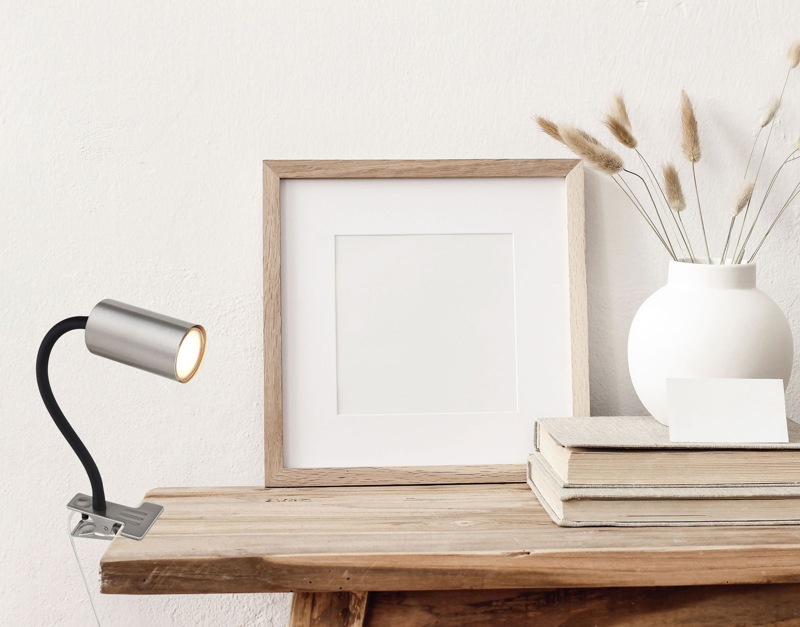 Globo Lighting Klemmstrahler ROBBY Klemmstrahler aus Metall in Nickeloptik, seitliche Perspektive, befestigt an einem Holztisch, neben einem Bilderrahmen und einer Vase.
